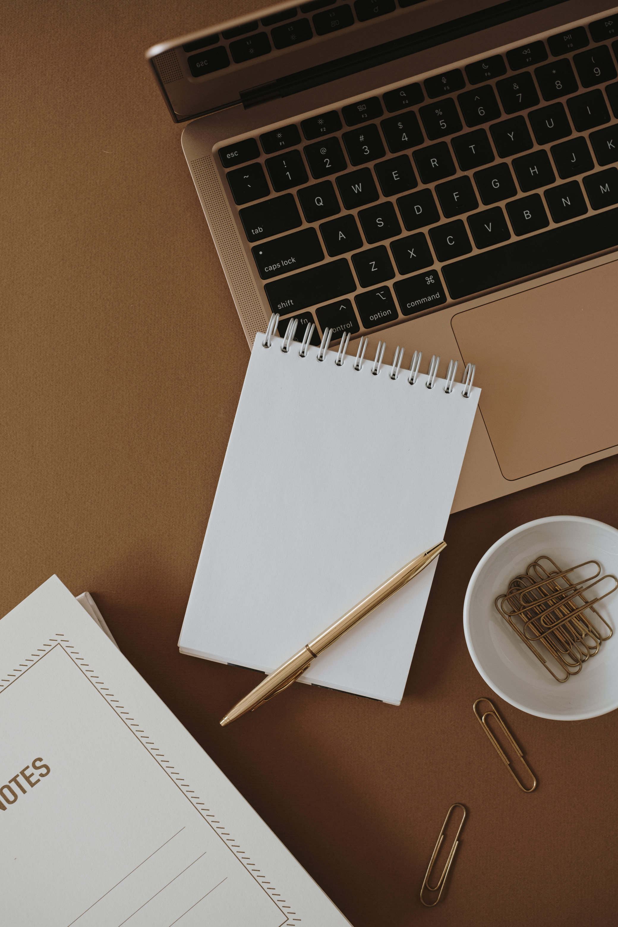 Notepad on Laptop on Brown Background